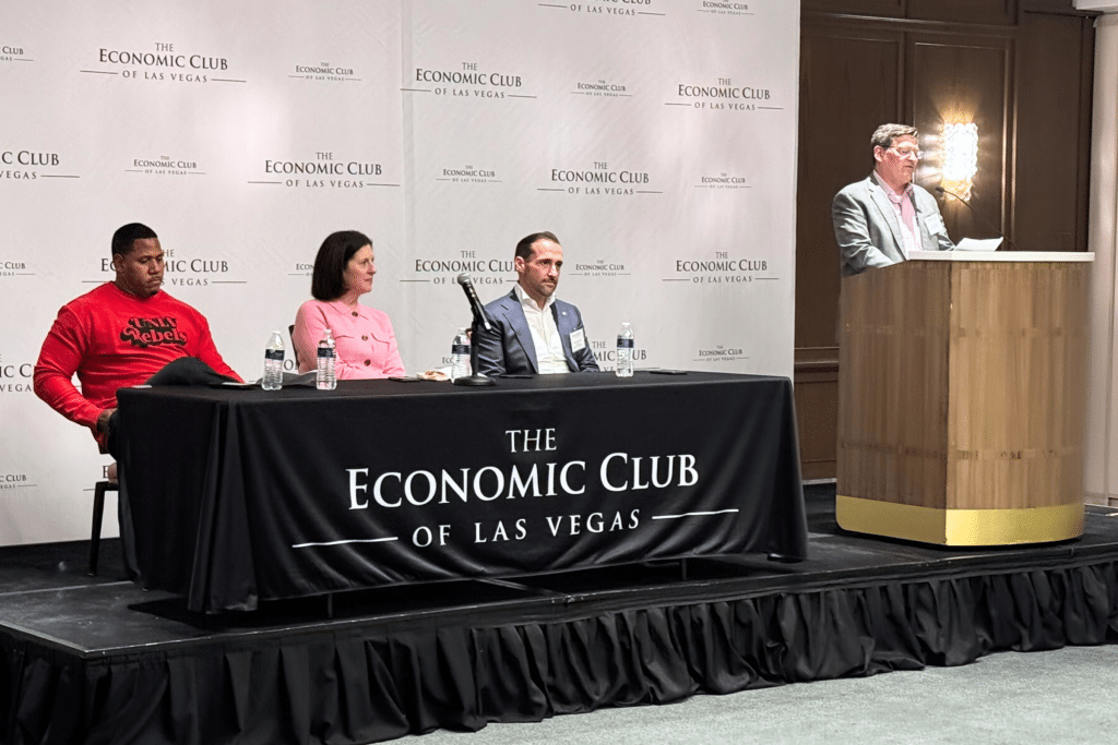 Four panelists sit on a stage with "The Economic Club of Las Vegas" banners and a black tablecloth.